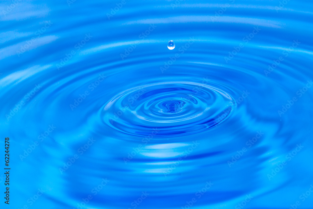 a drop of water falling in blue water. macro a drop of water falling in blue water. macro