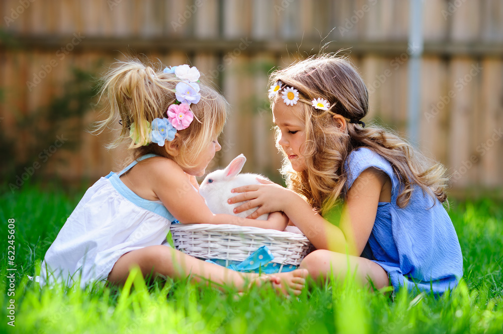 Fototapeta premium two little girl with a bunny rabbit has a easter at green grass