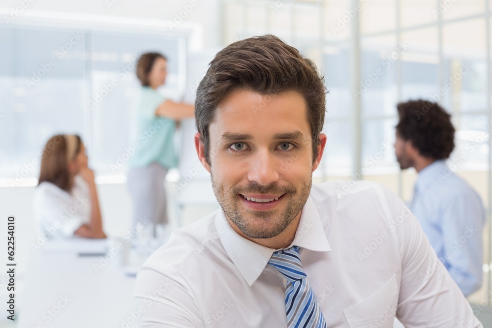 Smiling businessman with colleagues in meeting at office Smiling businessman with colleagues in meeting at office