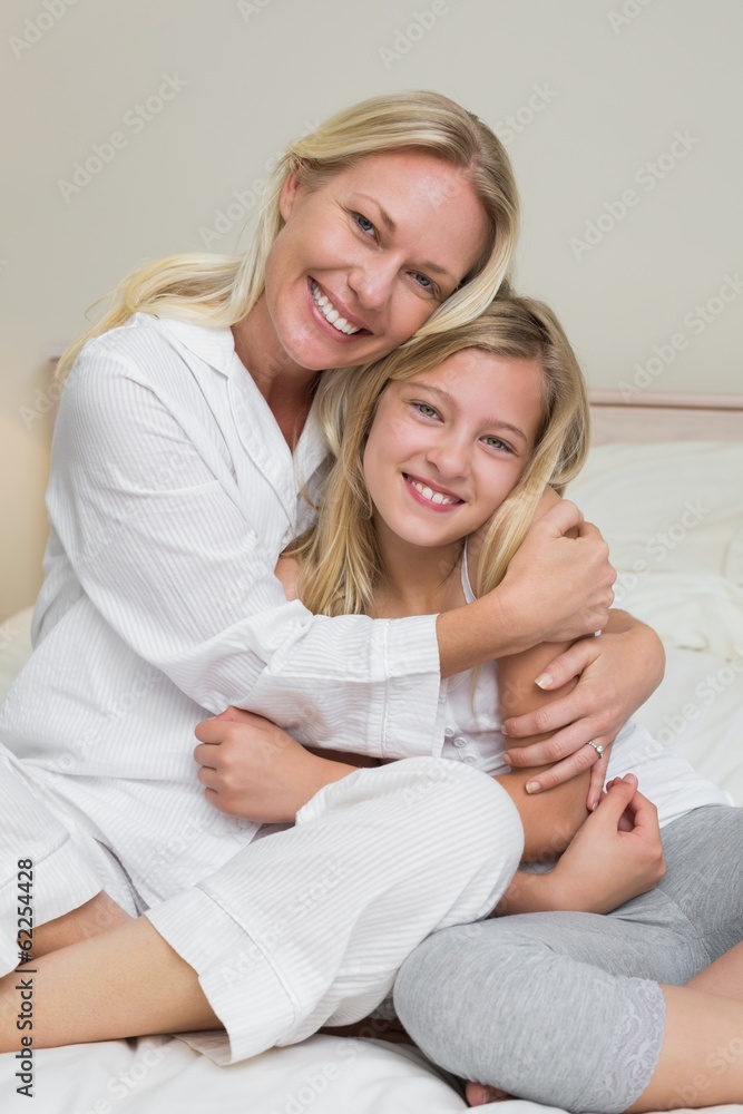 Happy mother hugging cute daughter in bed Happy mother hugging cute daughter in bed
