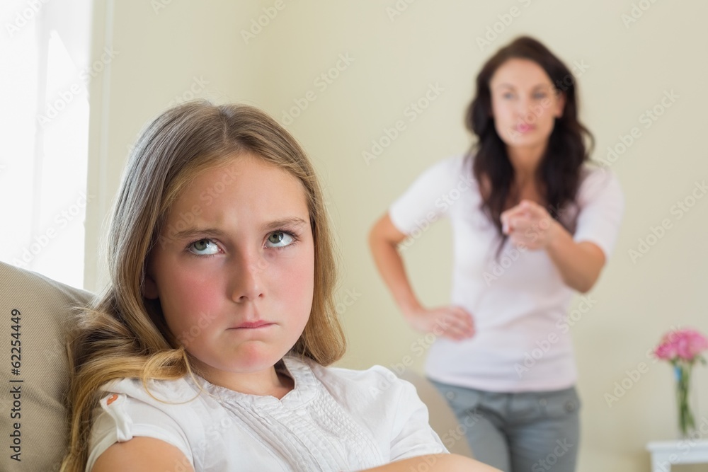 Angry girl with mother scolding her in background Angry girl with mother scolding her in background