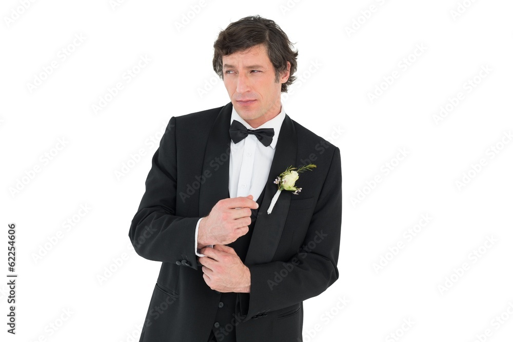 Groom in tuxedo adjusting cuff link Groom in tuxedo adjusting cuff link