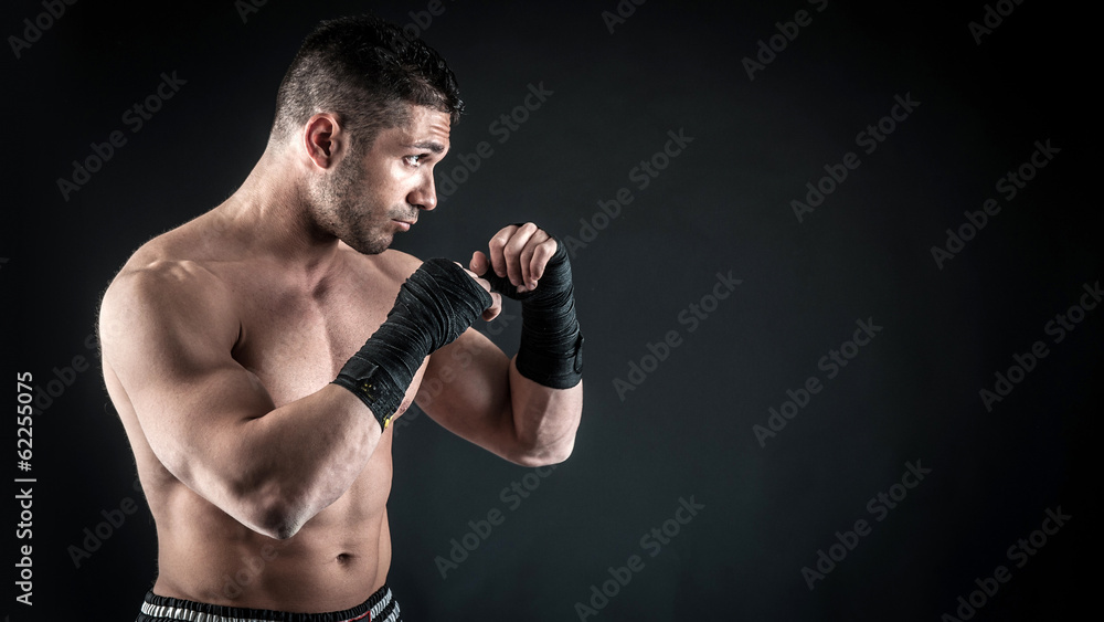 Sportsman kick boxer portrait against black background.