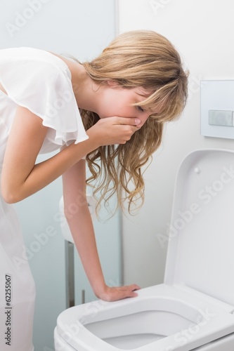 Young woman about to vomit into a toilet