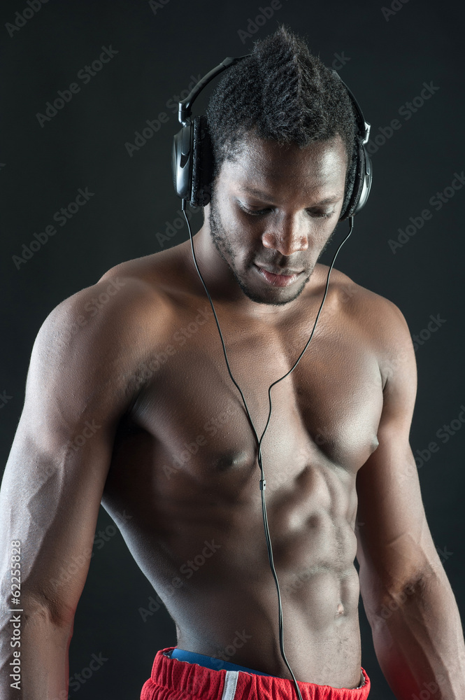 Obraz premium Black man with ear-phones against dark background.