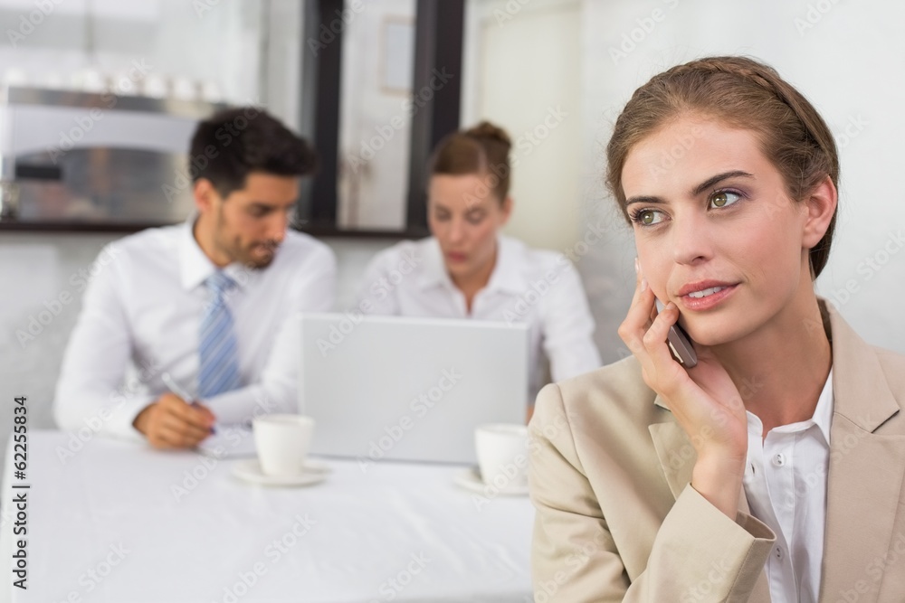 Businesswoman using mobile phone with colleagues at office desk Businesswoman using mobile phone with colleagues at office desk