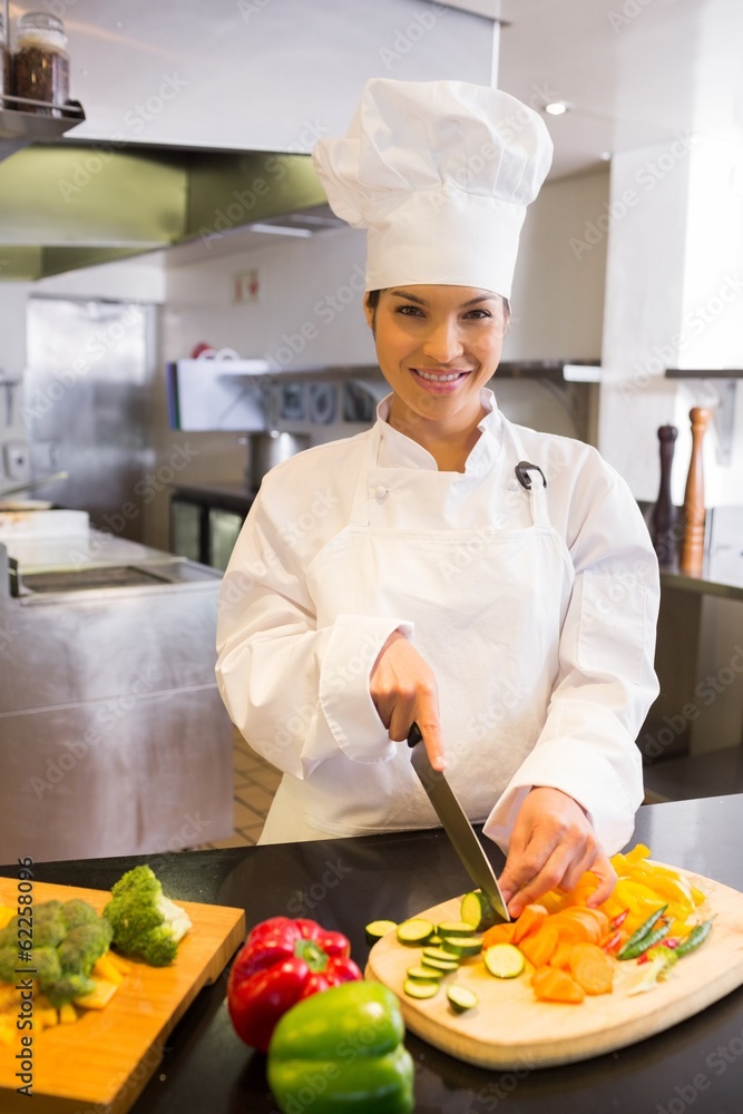 Smiling female chef cutting vegetables in kitchen Smiling female chef cutting vegetables in kitchen