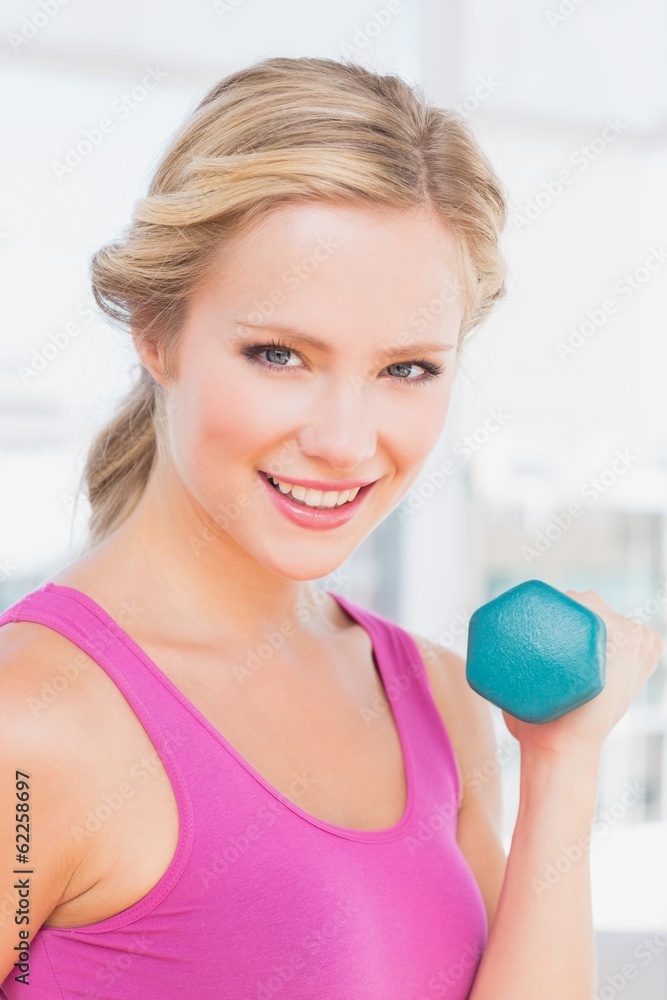 Cute blonde lifting dumbbells and smiling at camera Cute blonde lifting dumbbells and smiling at camera