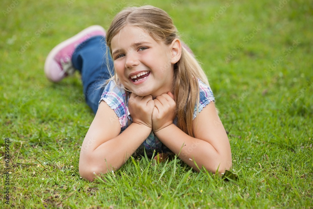 Happy young girl lying on grass at park Happy young girl lying on grass at park