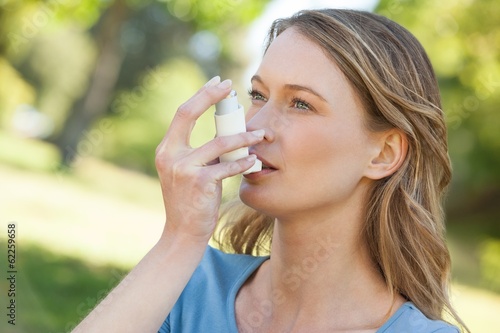 Woman using asthma inhaler in park photo