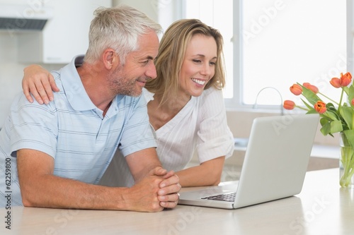 Cheerful couple using laptop together at the worktop © WavebreakmediaMicro