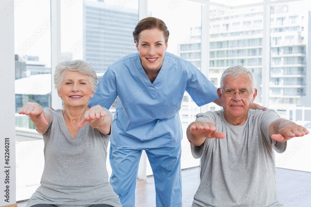 Female therapist assisting senior couple with exercises Female therapist assisting senior couple with exercises