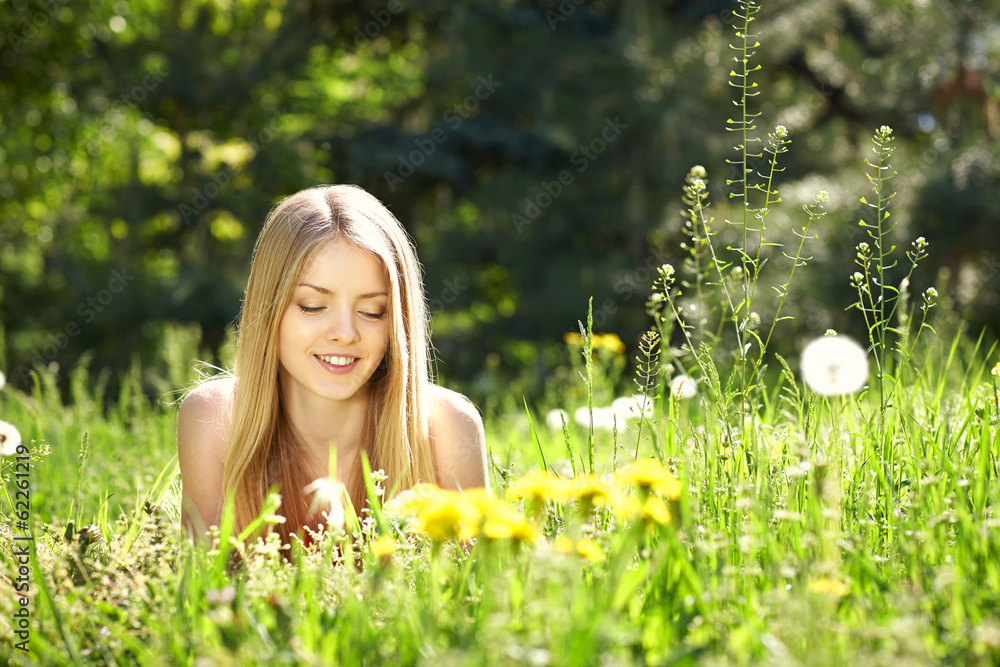 Spring girl lying on the field of dandelions Spring girl lying on the field of dandelions