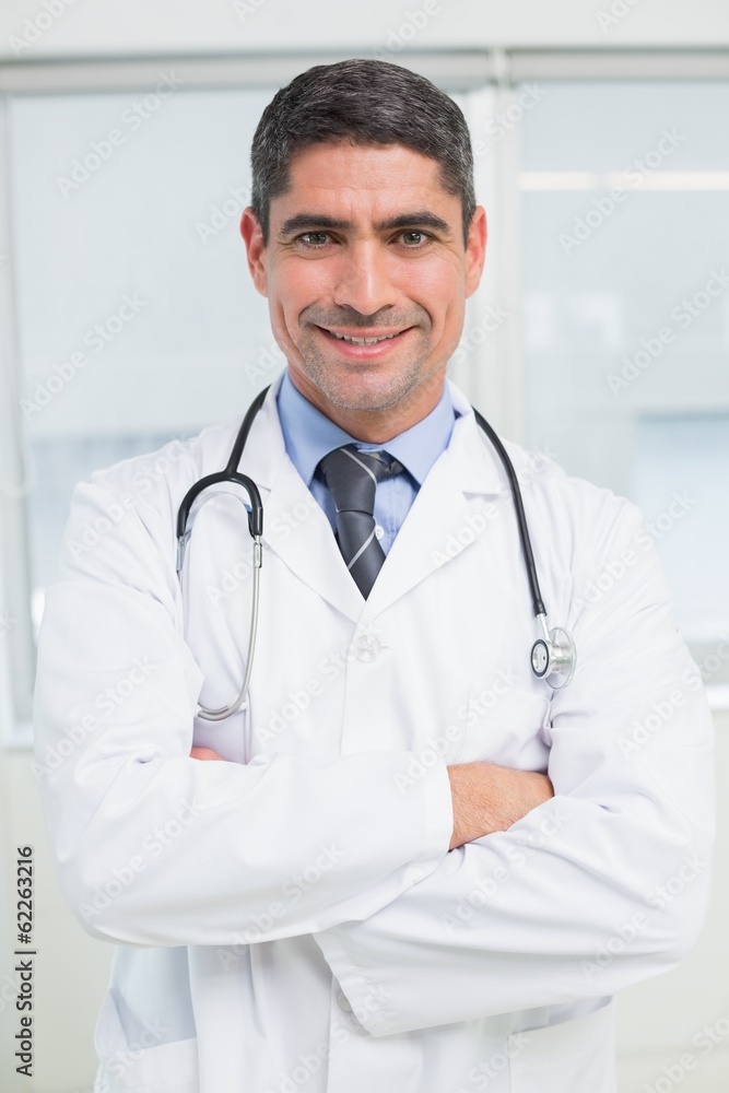 Smiling male doctor with arms crossed in hospital Smiling male doctor with arms crossed in hospital