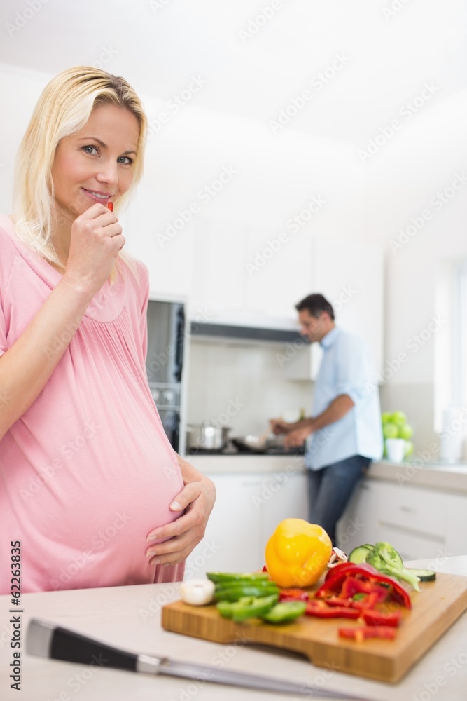 Pregnant woman with chopped vegetables and man cooking food Pregnant woman with chopped vegetables and man cooking food