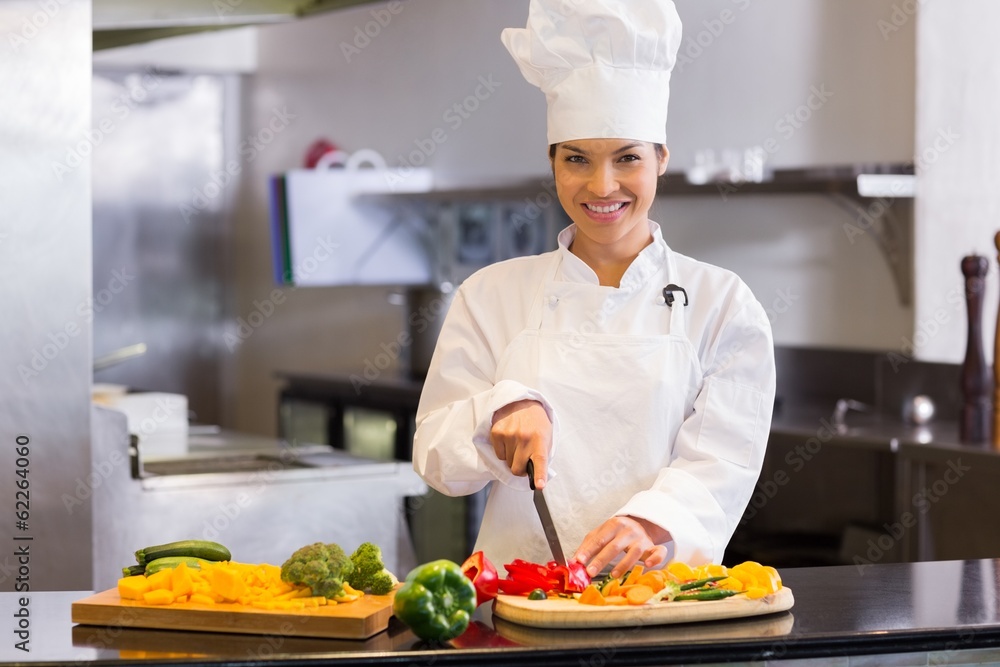 Smiling female chef cutting vegetables in kitchen Smiling female chef cutting vegetables in kitchen