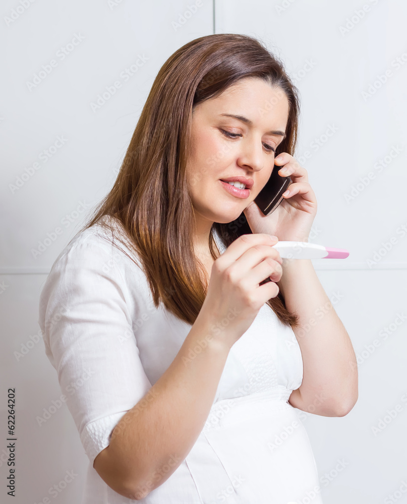 Woman with pregnancy test and talking by phone Woman with pregnancy test and talking by phone