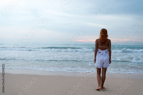 Young woman standing on ocean beach © Ni23