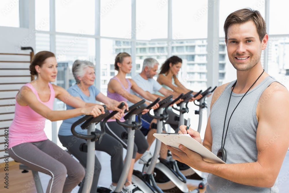 Trainer with people working out at spinning class Trainer with people working out at spinning class