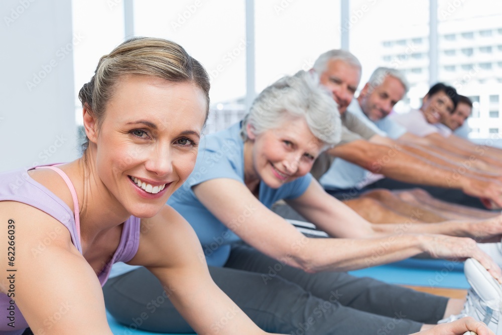 Class stretching hands to legs at yoga class Class stretching hands to legs at yoga class