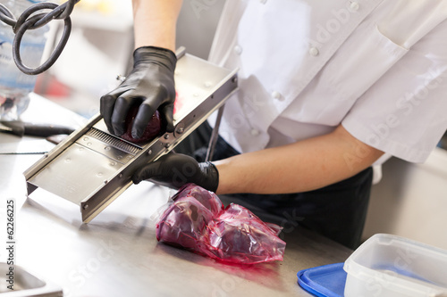 koch reibt frische rote beete an reibe mit handschuhen photo