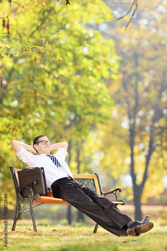 Relaxed businessman sitting on a bench in park Relaxed businessman sitting on a bench in park