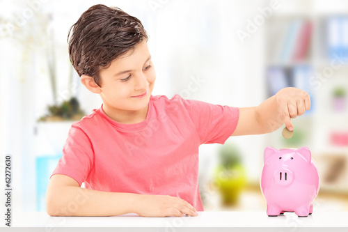 Boy inserting coins into a piggybank photo