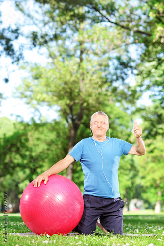 Man sitting in park with pilates ball