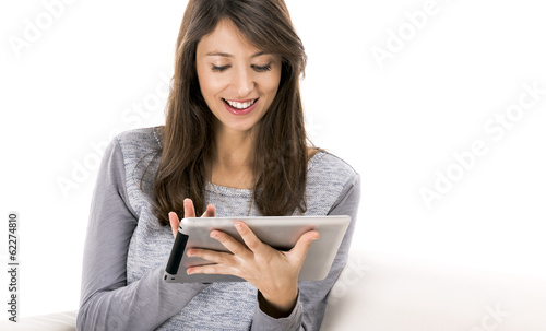 Beautiful woman sitting on the soda and working with a tablet