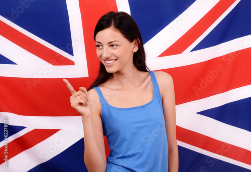 British girl smiling pointing to the side.UK flag background