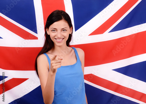 British girl smiling pointing in front to you.UK flag background