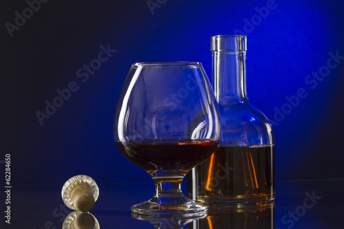 Cognac bottle and glass on the blue background.