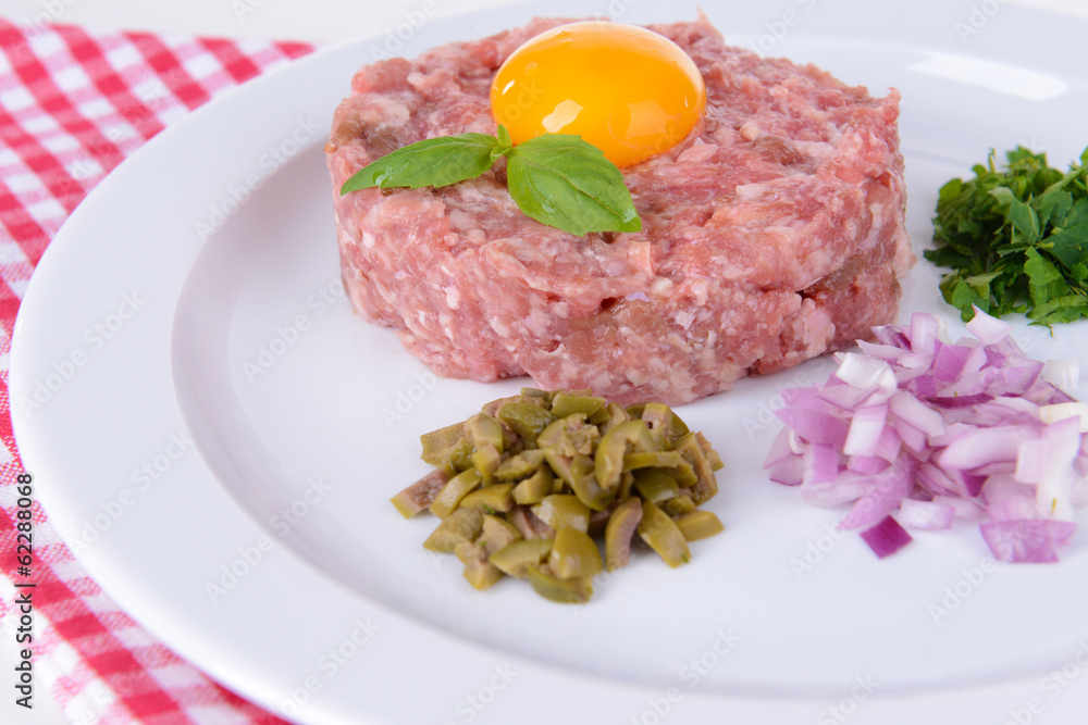 Delicious steak tartare with yolk on plate on table close-up