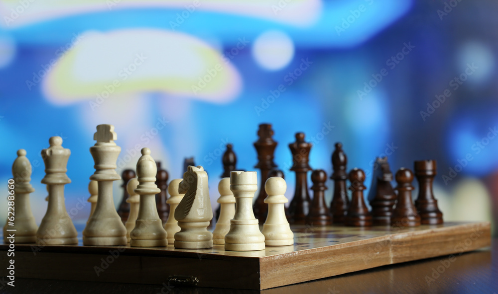 Chess pieces on board on bright background Chess pieces on board on bright background