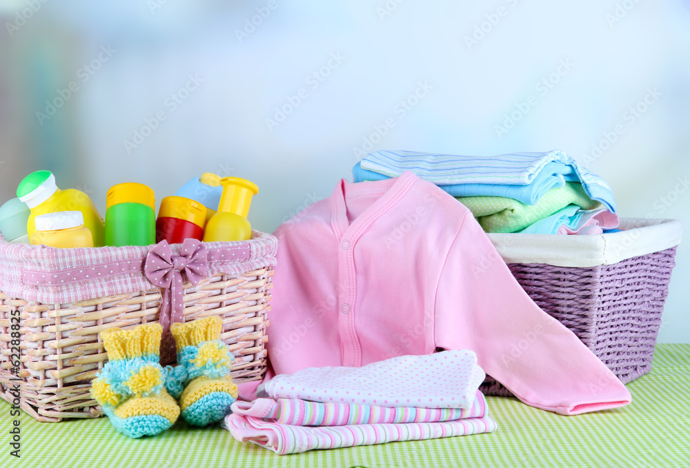 Pile of baby clothes in basket, on table on color background Pile of baby clothes in basket, on table on color background