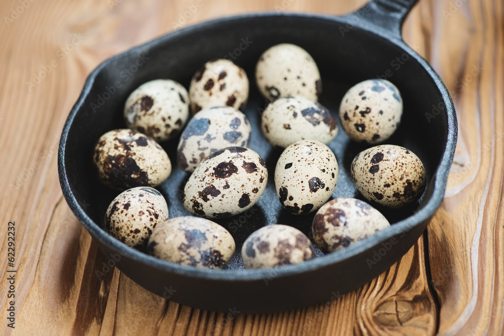 Close-up of a frying pan with raw quail eggs, horizontal shot Close-up of a frying pan with raw quail eggs, horizontal shot