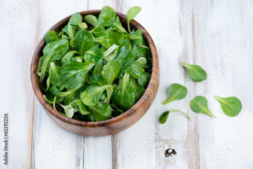 Wooden bowl with corn salad leaves  above view