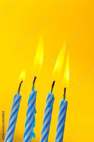 Four birthday candles over yellow background