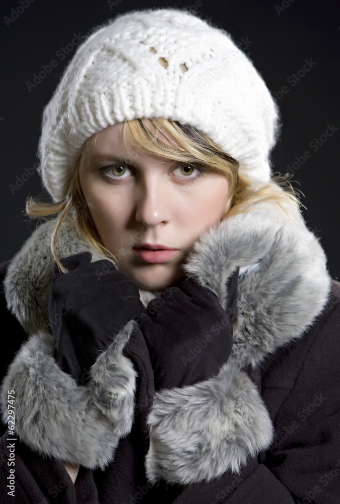 Girl in coat and white cap on black background. Winter, fur, col Girl in coat and white cap on black background. Winter, fur, col