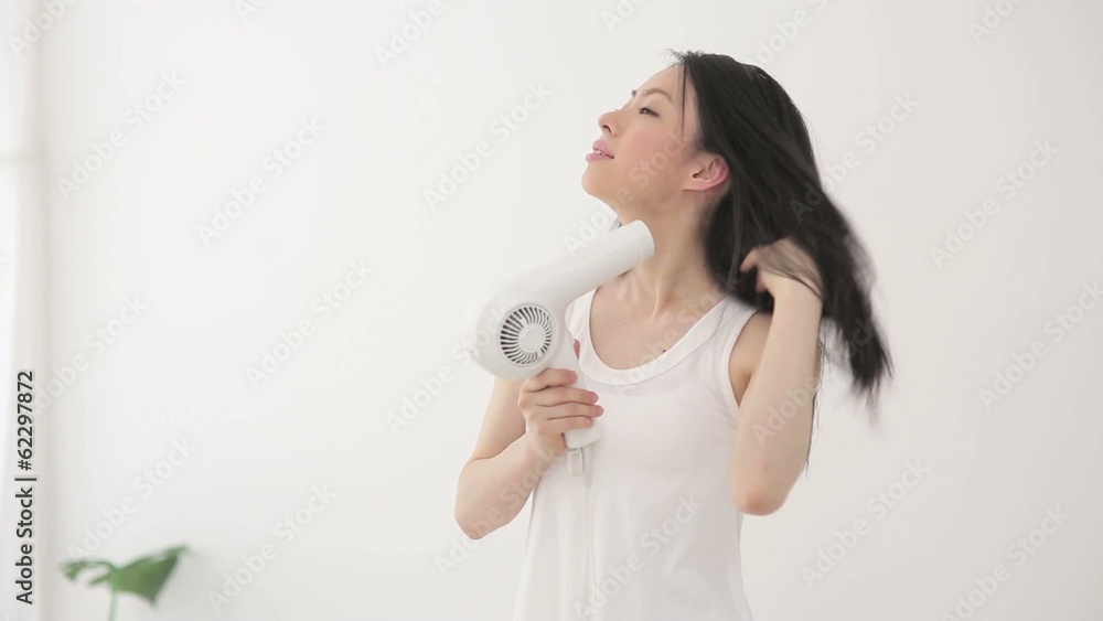 ドライヤーで髪を乾かす女性 ドライヤーで髪を乾かす女性