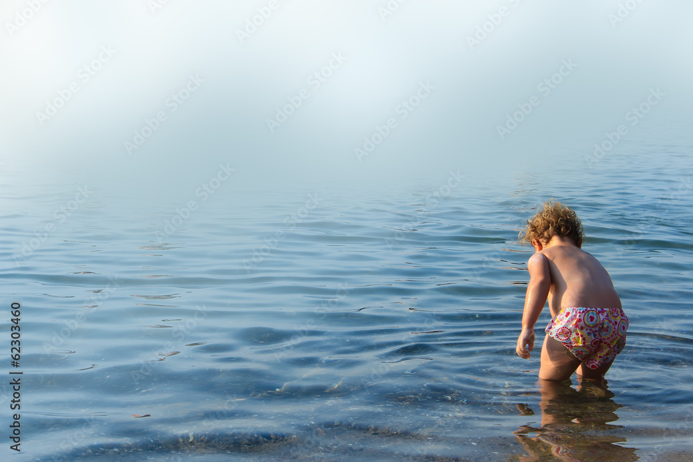 Cute kid playing in the watter on a blue background
