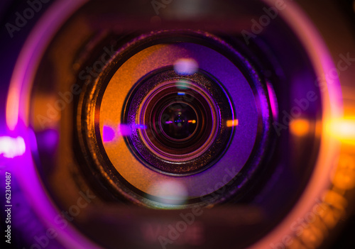 Video camera lens closeup lit by orange and purple neon light photo