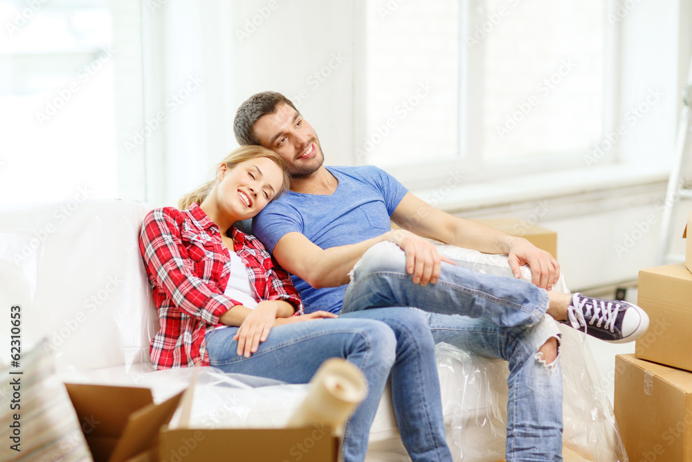 smiling couple relaxing on sofa in new home