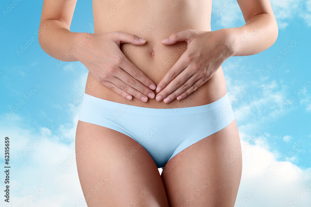 Woman's hands on stomach on sky background heart simbol Woman's hands on stomach on sky background heart simbol