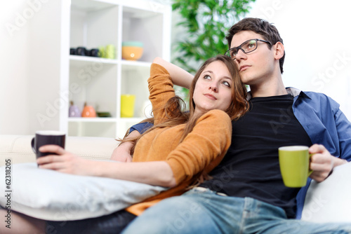 Lovely couple watching TV while drinking tea in their living roo