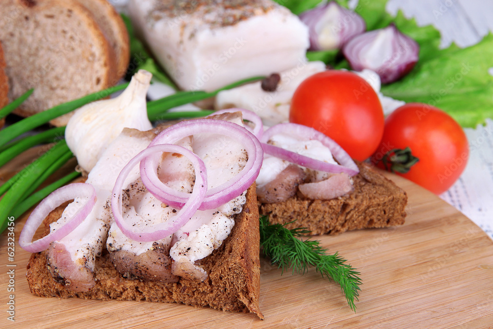 Slices of bread and lard with vegetables on table close up Slices of bread and lard with vegetables on table close up