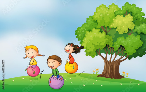 Three kids at the hilltop playing with the bouncing balls