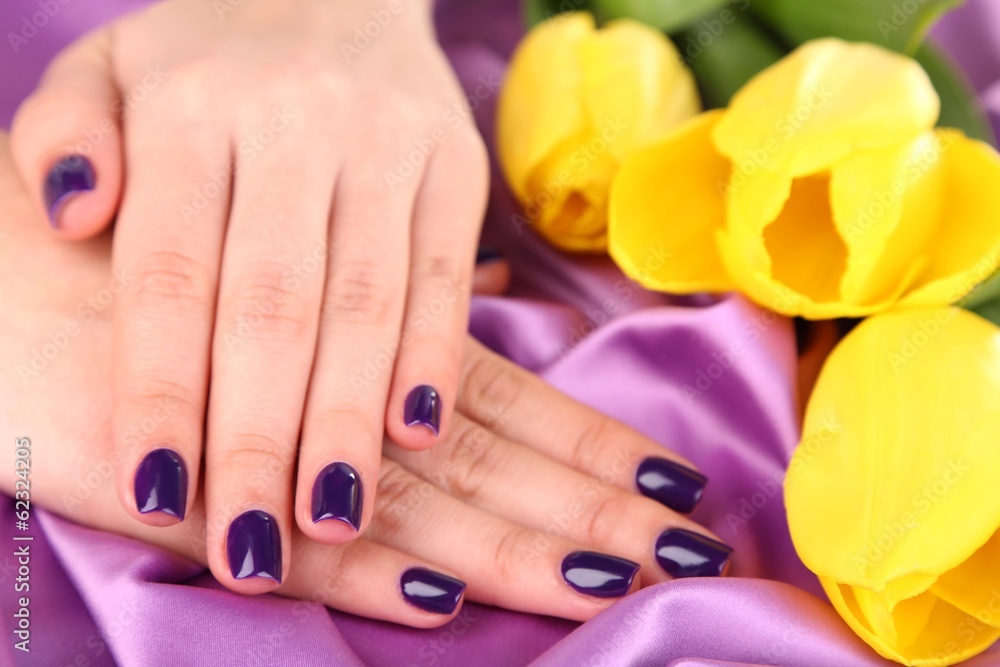Fototapeta premium Beautiful woman hands with flowers on fabric background