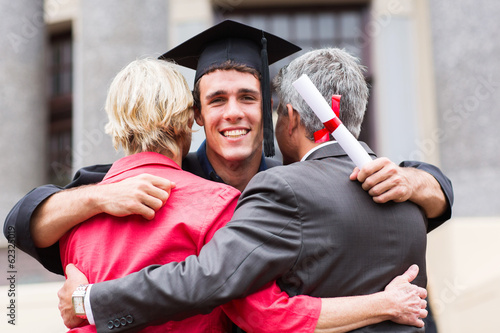 young male graduate hugging his parents photo