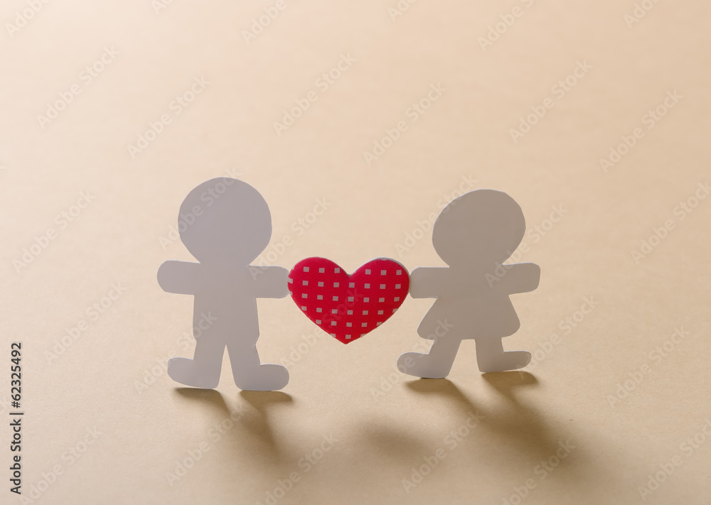 Silhouettes of men, women and heart cut out of paper on a wooden Silhouettes of men, women and heart cut out of paper on a wooden